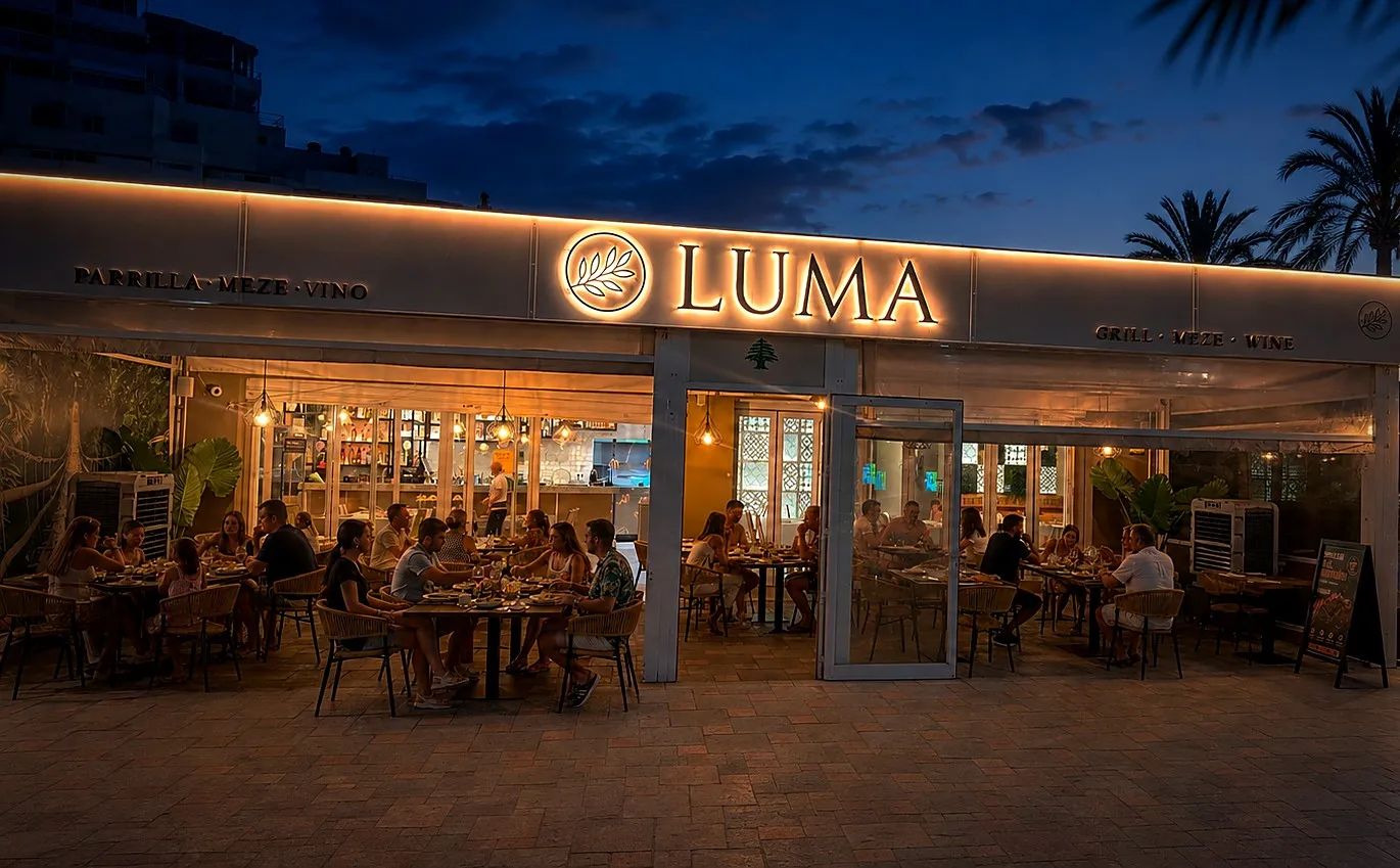 The lit facade of Luma at dusk, tables set on the terrace